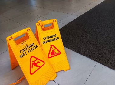 İki sarı tabela ıslak zemini uyardı ve halka açık alanda seramik zeminde temizlik yapılıyor. Kaymaları ve düşmeleri önlemek için güvenlik önlemi.