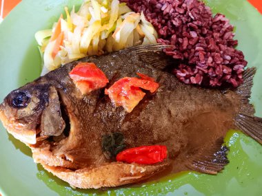 Endonezya yemeği, zerdeçal soslu kızarmış pomfret, kızarmış chayote, havuç ve yeşil tabakta esmer pirinç. Sağlıklı gıda konsepti.