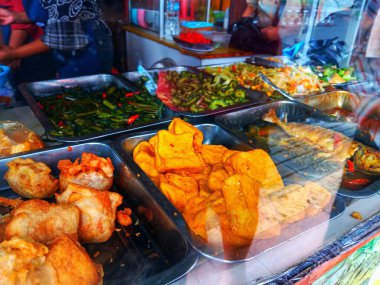 Endonezya mutfağının ev yapımı yemekleri cam kutuda uygun fiyatlarla sergilenen çeşitli yemekler sunuyor. Kapat..