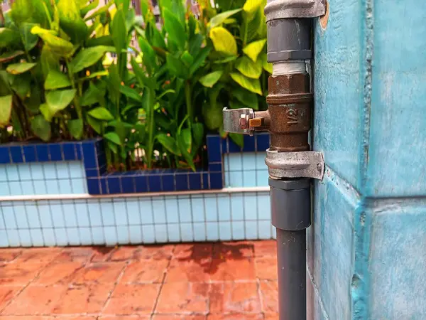 Açık hava duş vanası ya da musluk yüzme havuzunun mavi duvarına monte edilmiş..