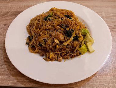 Çin yemeği, Bihun goreng olarak da bilinir. Karıştırılmış pirinç vermicelli, kızarmış yumurta, tavuk ve turşu ile ahşap arka planda izole edilmiş beyaz tabak..