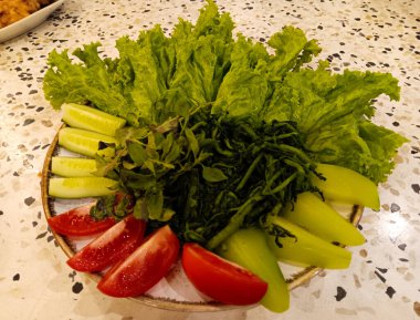Terrazzo masasında izole edilmiş Endonezya mutfağında genellikle salata ya da Lalapan olarak servis edilen bir tabak taze sebze..