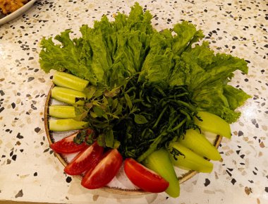 Terrazzo masasında izole edilmiş Endonezya mutfağında genellikle salata ya da Lalapan olarak servis edilen bir tabak taze sebze..