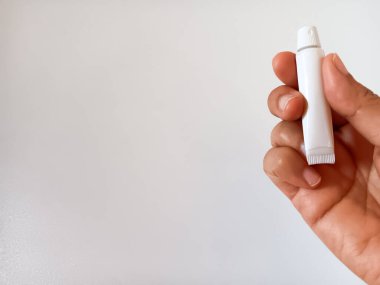 Beyaz arka planda izole edilmiş küçük beyaz tüp diş macunu tutan kadının eli. Metin için alanı kopyala.