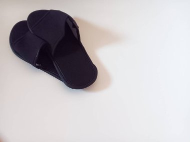 Beyaz arka planda izole edilmiş bir çift siyah tek kullanımlık otel terliği..