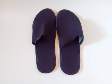 Beyaz arka planda izole edilmiş bir çift siyah tek kullanımlık otel terliği..