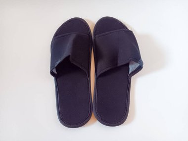 Beyaz arka planda izole edilmiş bir çift siyah tek kullanımlık otel terliği..