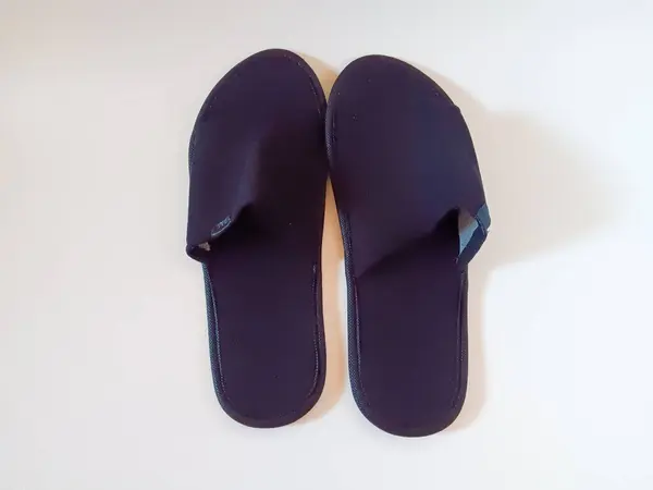 Beyaz arka planda izole edilmiş bir çift siyah tek kullanımlık otel terliği..