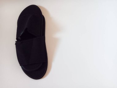 Beyaz arka planda izole edilmiş bir çift siyah tek kullanımlık otel terliği..