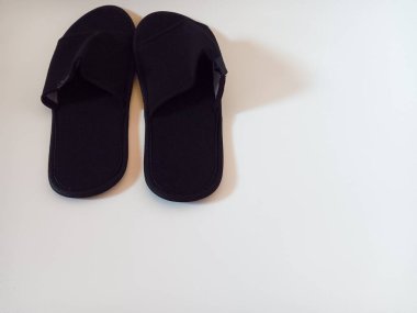 Beyaz arka planda izole edilmiş bir çift siyah tek kullanımlık otel terliği..