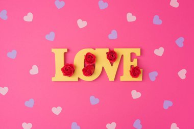 Pembe ve mor kalp deseni, kağıt kesiği romantik konsept, üst görünüm. Pastel pembe arka planda kırmızı güllerle güzel sarı bir aşk. Sevgililer Günü tebrik kartı konsepti. Düz uzanma sanatı.
