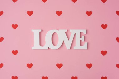Kırmızı kalp deseni, romantik konsept, üst manzara. Pastel pembe arka planda, ortası beyaz aşkla dolu güzel kalpler. Sevgililer Günü tebrik kartı sanatı. Düz konum
