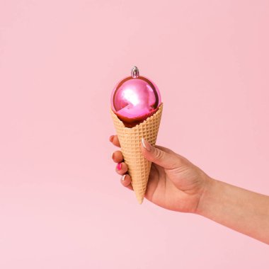 Açık Pembe Arka Grubundaki El Tarafından Tutulan Konifedeki Parlak Pembe Balo, Gerçeküstü bir ziyafeti gösteren Kavramsal tatil resmi.