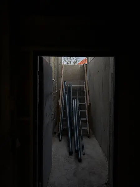 Ahşap merdivenlerde uzanan metal borular binaya yerleştirilmeye hazır. Mavi yakalı işçiler yangın söndürme sistemi kuruyor.