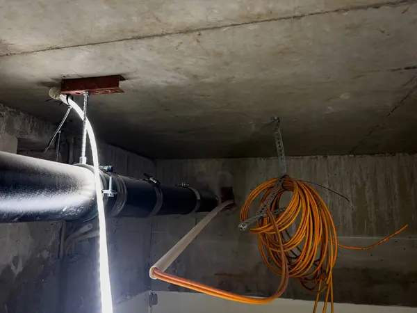 Çimento duvarından geçen bir tavana kablo döşemesi 