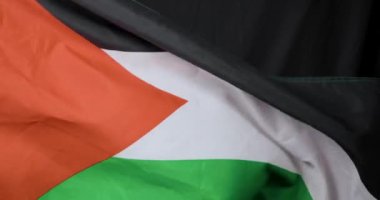 Bu video Filistin bayrağının siyah bir arkaplanda dalgalandığını gösteriyor, yakın plan çekimleri canlı renkleri ve detaylarını vurguluyor
