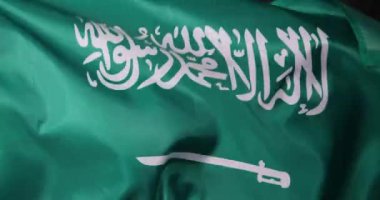 Suudi Arabistan 'ın güzel bayrağı zarif bir şekilde rüzgarda sallanıyor, zengin yeşil rengini ve belirgin amblemini sergiliyor.