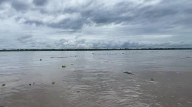 Iquitos yakınlarında yüzen enkaz ve bulutlu Amazon Nehri manzarası. Yüksek kalite 4k görüntü