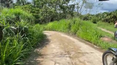 Heyecan verici bir yolculuk başlıyor. Bir motosiklet sürücüsü uzun otlar ve ağaçlarla çevrili manzaralı toprak bir yolda yürüyor. Özgürlüğü ve keşfi somutlaştırıyor.