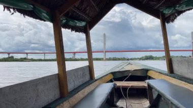 Güzelce hazırlanmış bir tekne sakin bir nehirde nazikçe yüzüyor. Arka planda güzel bir köprü var.