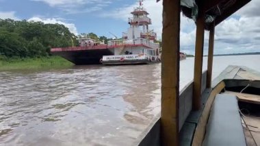 Videoda, nehir manzarasını güzelleştiren, rıhtımda büyük bir teknesi ve yakındaki iki teknesi olan sakin bir su yolu var.