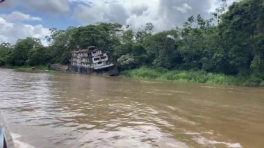 Bu büyüleyici video, yemyeşil ve ağaçların arasında süzülen büyük bir teknenin yer aldığı huzurlu bir nehir manzarasında huzurlu bir yolculuk sergiliyor.