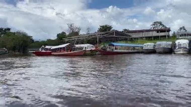Editör Amazon Nehri teknelerini nehir kenarındaki binaların önüne yanaştırdı. Yüksek kalite 4k görüntü