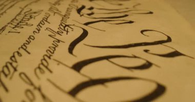 Bu video, kağıt üzerinde zarif yazılar, ABD Anayasası 'nın önemi ve kişisel notların vurgulanması ile başlayan yakın çekimler yoluyla kaligrafiyi gösteriyor.