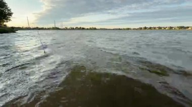 Bu büyüleyici videoda, bir insan sakin bir gölde huzurlu bir balık tutma gününün tadını çıkarıyor, doğal güzelliklerle çevrili, sergilenen bir rahatlama