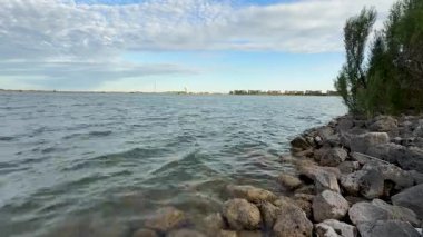 43 Sunlight on Shoreline Rocks as Gentle Waves Roll Lake. Yüksek kalite 4k görüntü