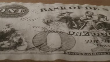 Bu siyah beyaz video, bir dolarlık banknot ve sahte bir De Soto Bankası notu sergilenerek para birimini araştırıyor, nostalji ve entrika çağrıştırıyor.
