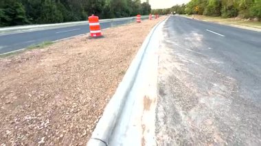 Video, güvenlik için doğrudan trafiği yönlendiren turuncu ve beyaz trafik konilerinin yer aldığı bir inşaat alanını gösteriyor.