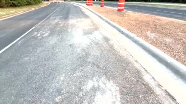 Video, beton kaldırım ve gerçekçilik için renkli işaretler içeren koni ve variller gibi trafik kontrol unsurlarıyla dolu bir yol tasvir ediyor.