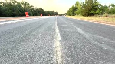 Boş bir yol ve arka planda ağaçlar olan sakin bir otoyol. Sakin bir manzarada özgürlüğün ve maceranın altını çizen bir araba pürüzsüz bir şekilde sürer.