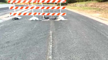 Video, kapanışını işaretleyen beyaz ve turuncu bir barikatla terk edilmiş bir yolu tasvir ediyor. Kapalı Yol tabelasına ve terk edilmiş bir hissi artıran beyaz çizgiye odaklanıyor.