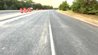 Dinamik bir videoda turuncu konili boş bir otoyol yer alıyor ve beklenti yaratıyor. Kamera, yolculuk ve maceraya rehberlik eden konileri vurguluyor.