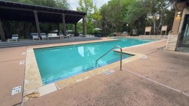 Bu video, geniş bir yüzme havuzu, davetkar merdivenleri, rahat sandalyeleri, bereketli ağaçları ve büyüleyici bir çardağı olan huzurlu bir yerleşim alanını içeriyor.