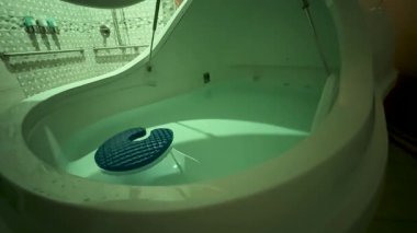 Sakinleştirici bir video, rahatlatıcı bir banyo atmosferiyle çevrili, mavi minderli, rahatlatıcı bir banyo küvetinde yüzen birini gösteriyor.