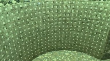 This video showcases a serene bathroom with a luxurious bathtub, mosaic tile wall, shower design, artistic shadows, and playful green fabric