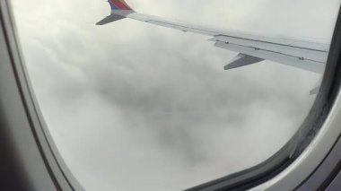 Bu büyüleyici videoda bulutların üzerinde süzül. Kamera, kabarık bulutların arasında süzülen bir uçak kanadı yakalar ve hava güzelliğini gösterir.