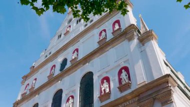 Bu video açık mavi gökyüzünün altında büyük beyaz bir bina gösteriyor, kayan kamera açıları onun ihtişamını ve dingin atmosferini gösteriyor.