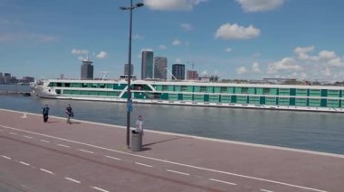 Amsterdam, Hollanda 29 Temmuz 2025: Amsterdam kıyısı boyunca modern binaların bisiklet yolu geniş görünümü