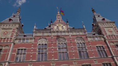 Amsterdam, Hollanda 29 Temmuz 2025: Tarihi bina üzerinde saat ve gökkuşağı bayrağıyla gotik cephe