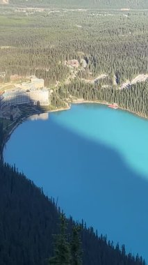 Denemelerle çevrili mavi göl ve kenarda oteli olan dağlar. Louise Gölü 'ne tepeden bakan manzara, Kanada' nın Alberta kentindeki Banff Ulusal Parkı 'nda bulunan mavi bir göl.