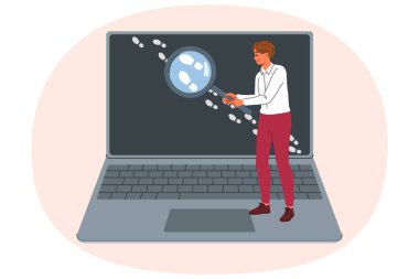 Adam internette iz arıyor, OSINT uzmanı olarak çalışıyor ve bilgisayar ekranının yanında büyüteç tutuyor. Dedektif OSINT tekniklerini açık kaynakları kullanarak keşif için kullanır.