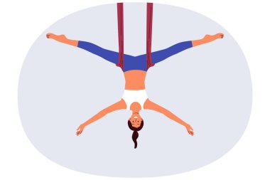 Kadın hava yogası yapıyor, vücut sağlığı ve esnekliğini geliştirmek için esneme egzersizleri yapıyor. Hava yogası eğitmeni kız pilates ya da aerobik kurslarına yazılmasını öneriyor.