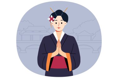 Geleneksel Japon kimonosu giymiş geyşa kadın, geleneksel doğu binalarıyla parkın yakınında durarak konishua jesti yapıyor. Asya ülkesinden gelen geyşalar selamlama işareti olarak göğsünün önünde avuçlarını büker.