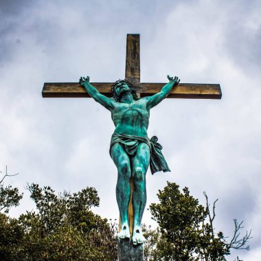 Çarmıhtaki İsa Mesih, bronz anıt, gökyüzü ve arkadaki ağaçlar.