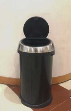 Çöp kutusu açık ve boş. Duvarın önündeki çöp tenekesi..