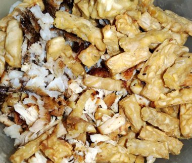 Pirinçli bir kase yiyecek ve Tempe dediğimiz işlenmiş soya fasulyesi. Temposu küçük parçalara ayrılır ve sıcak pirinçle karıştırılır. Kase dolu ve yemekler lezzetli görünüyor.